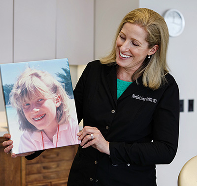 Dr. Meridith Long holding a portrait of a girl with braces